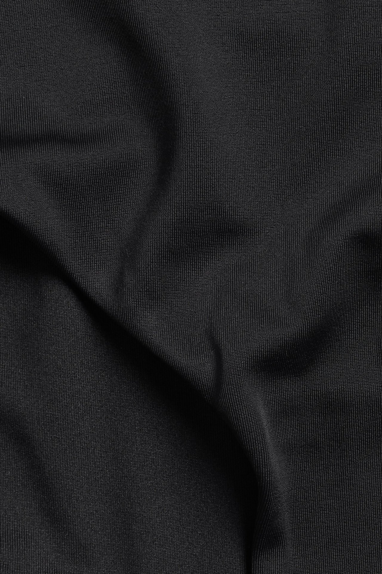 Zbliżenie czarnego, jednolitego materiału od stroju kąpielowego z drobną prążkowaną fakturą.