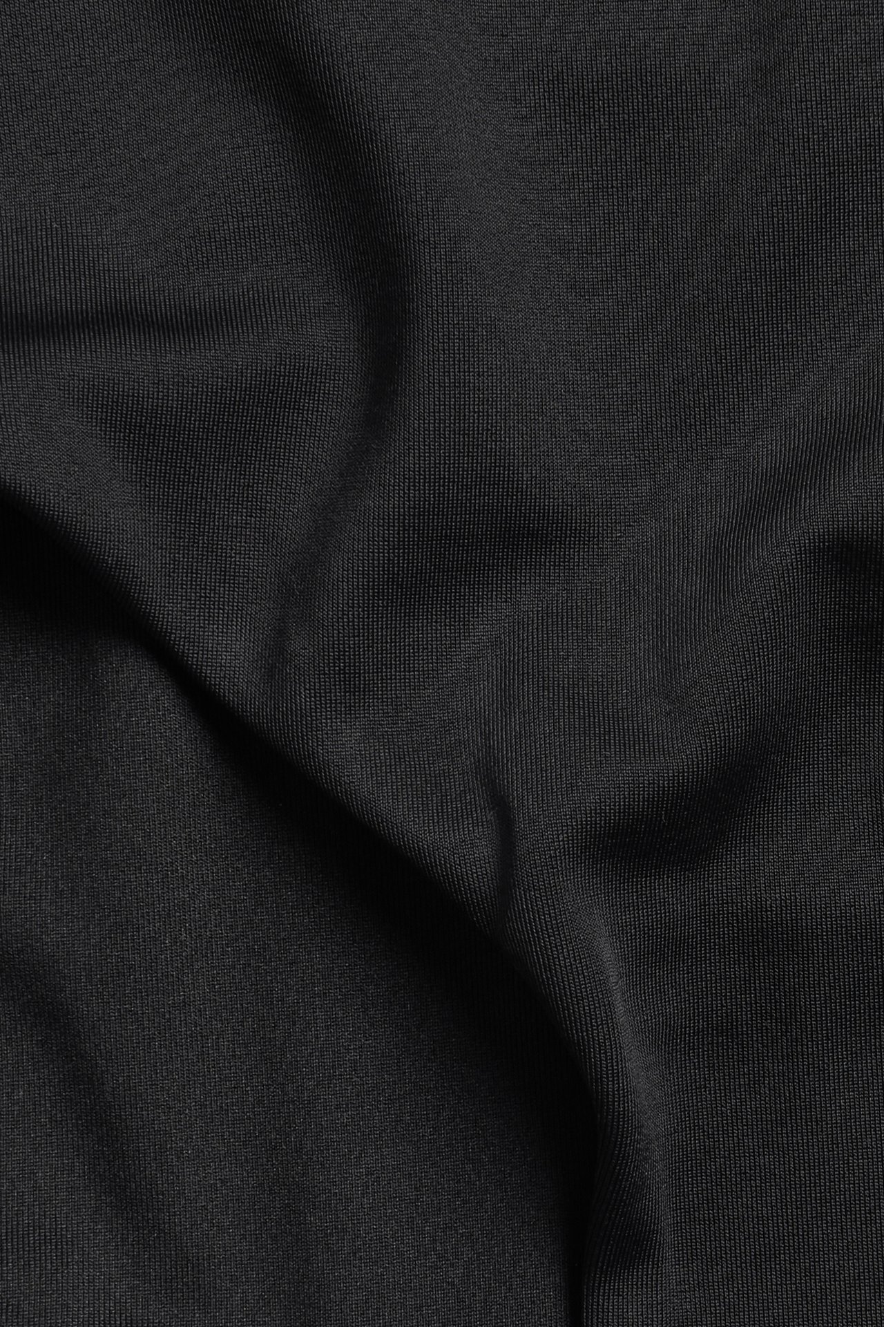 Lähikuva mustasta, ribatusta, yksivärisestä muokkaavasta bikinikankaasta, jossa on pehmeitä poimuja.