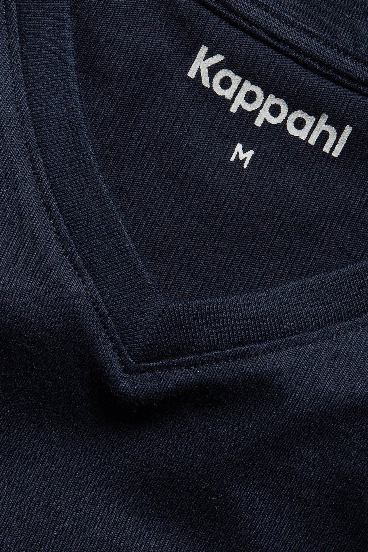 Zbliżenie na granatowy bawełniany T-shirt z dekoltem w serek i białą metką Kappahl.