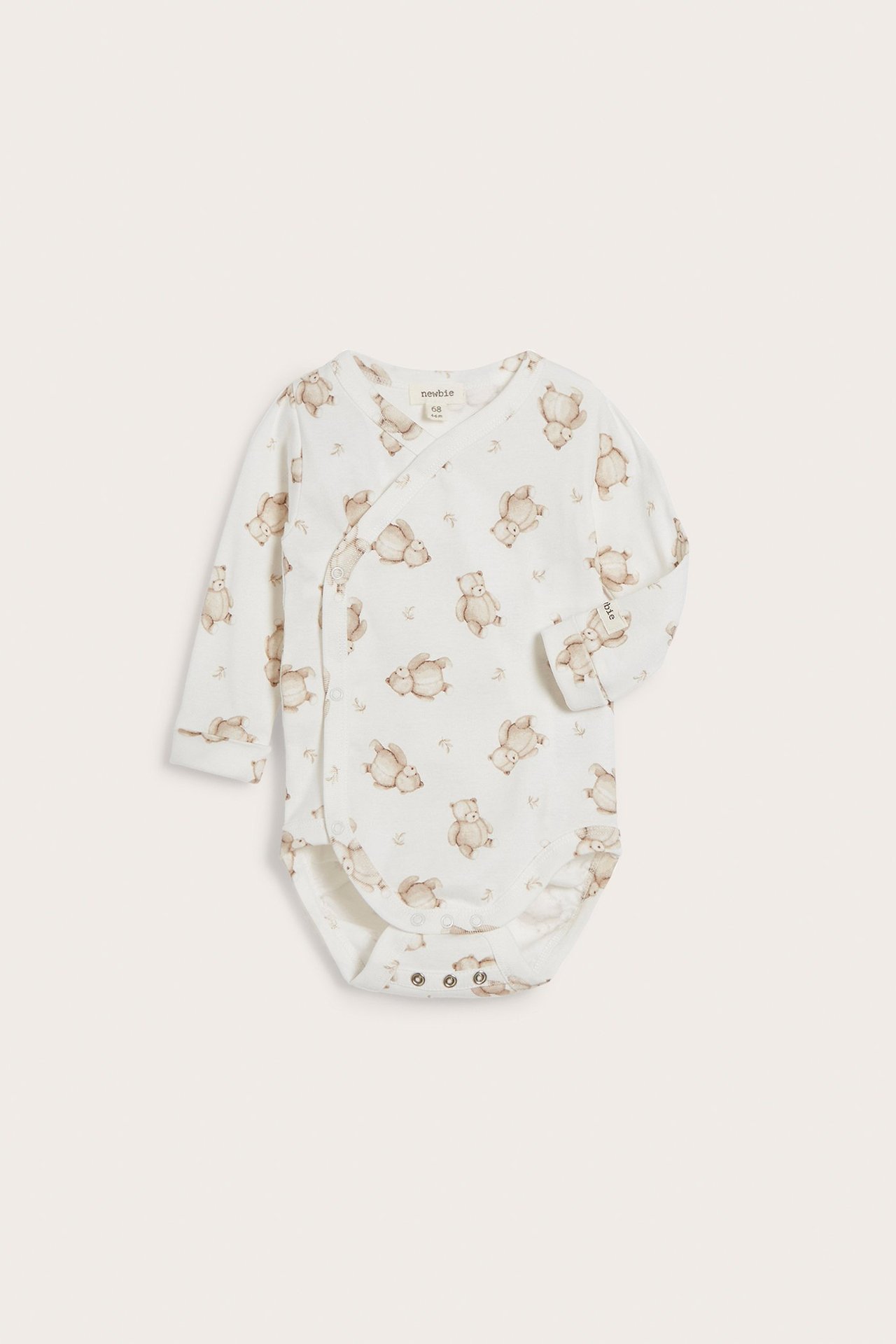 Framifrån: Offwhite omlottbody för baby med långa ärmar, brunt nallemönster och tryckknappar.