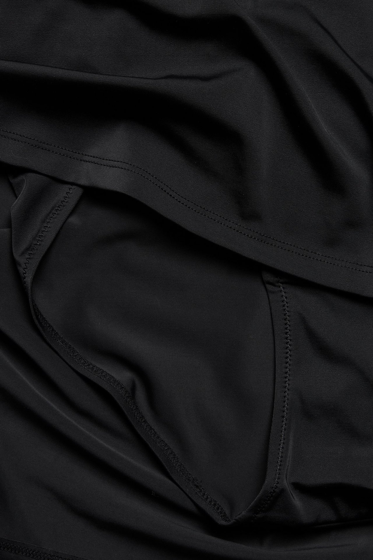 Zbliżenie czarnej, jednolitej spódniczki kąpielowej z majtkami, ukazujące gładki materiał i szwy.