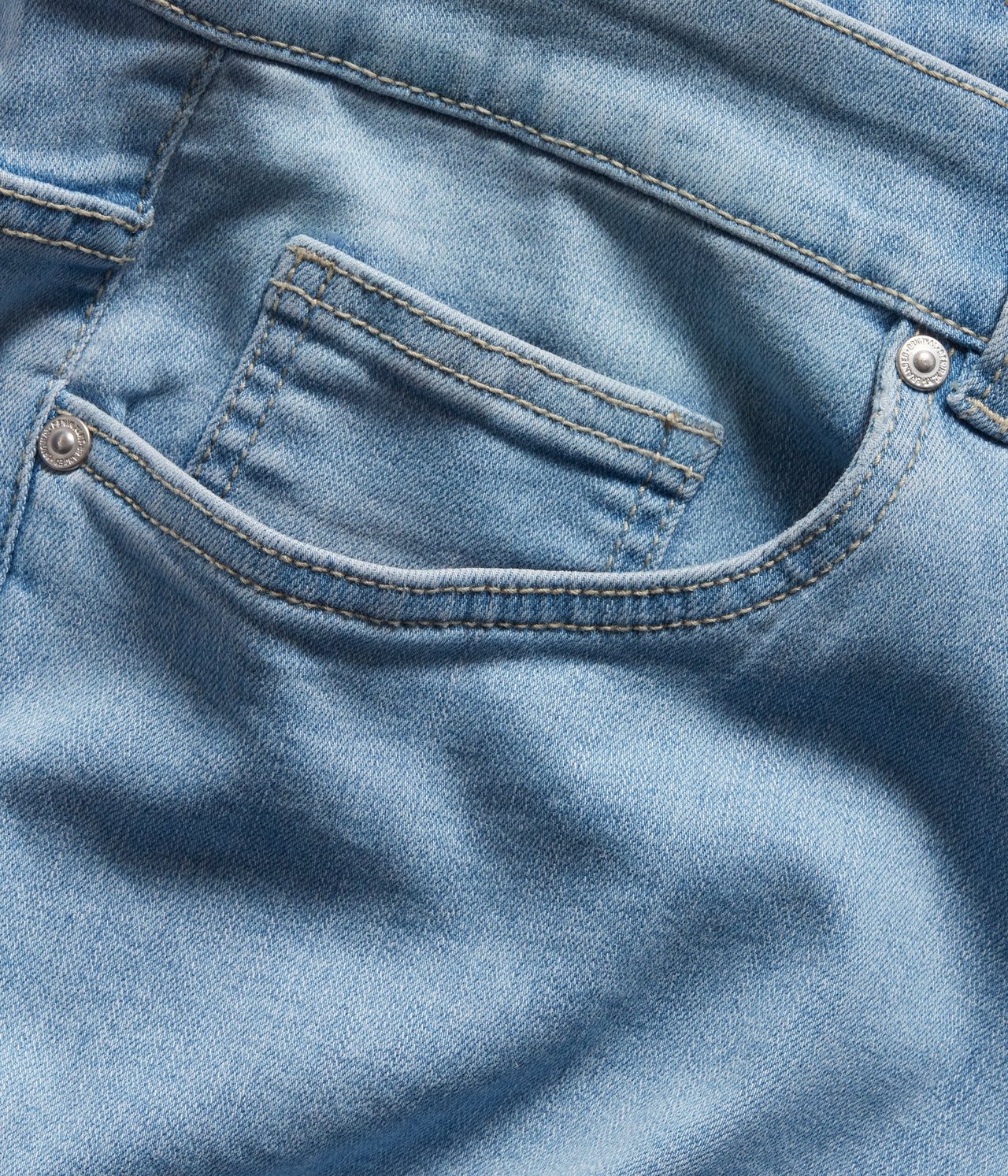 Zbliżenie jasnoniebieskich jeansów bootcut, ukazujące przednią kieszeń ze szwami i metalowymi nitami.