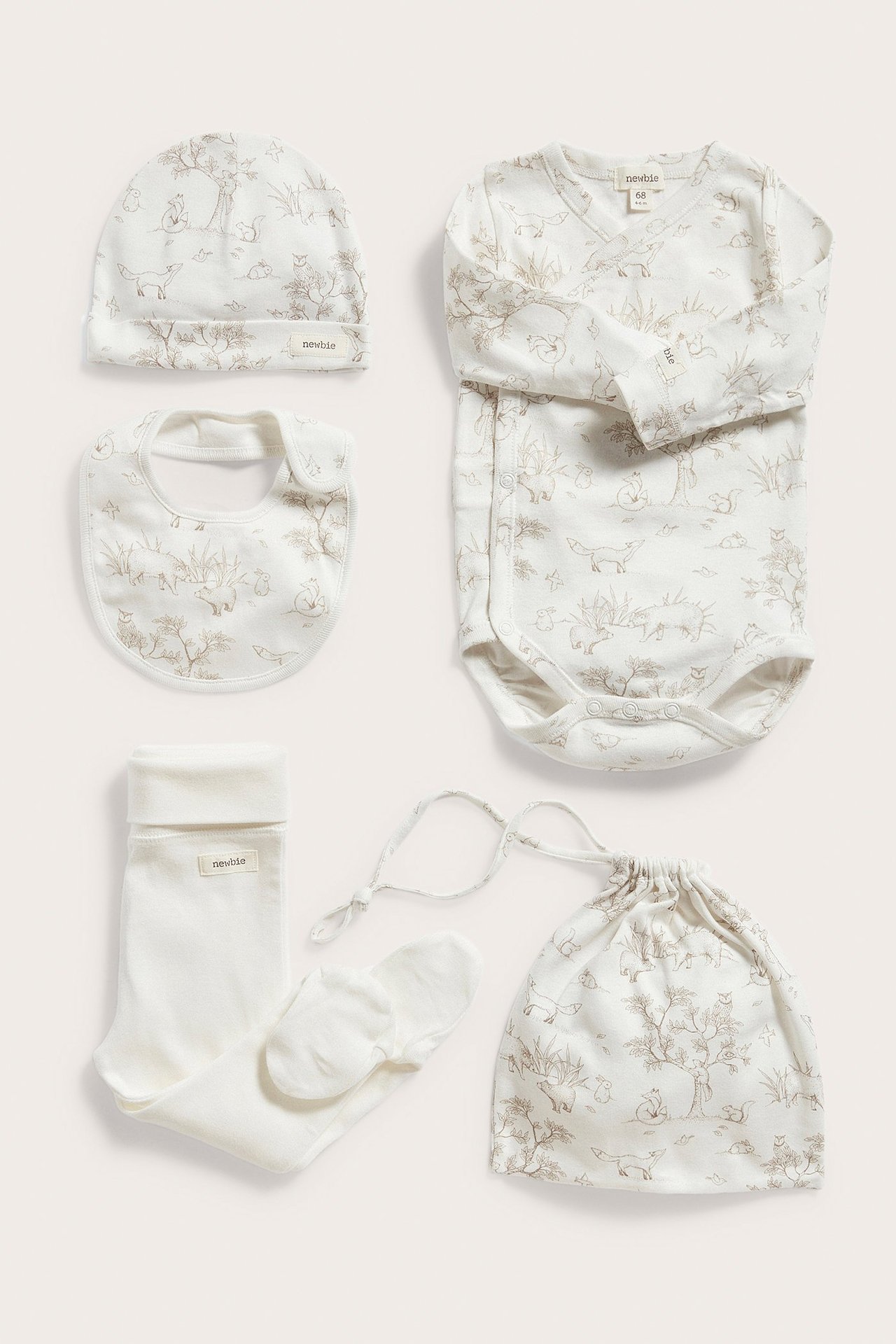 Off-white babygåvoset i bomull: mönstrad långärmad omlottbody, matchande mössa, haklapp, påse, byxor, strumpor.