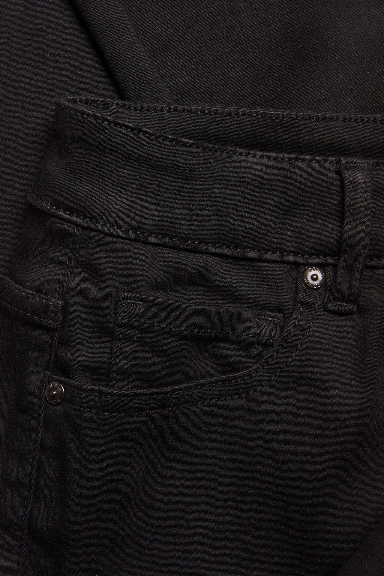 Zbliżenie na czarne jeansy z wysokim stanem i prostymi nogawkami, z przednimi kieszeniami i nitami.