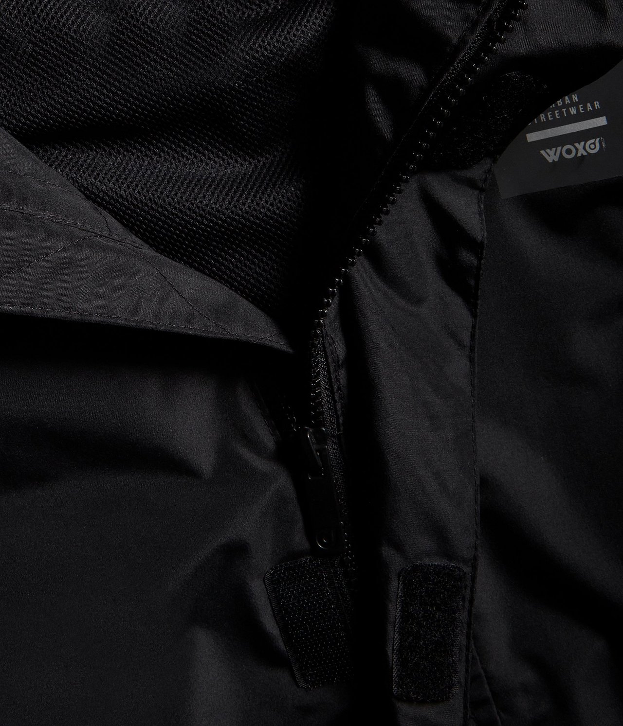 Zbliżenie czarnej wodoodpornej kurtki softshellowej, ukazujące zamek błyskawiczny, podszewkę z siatki i rzep.