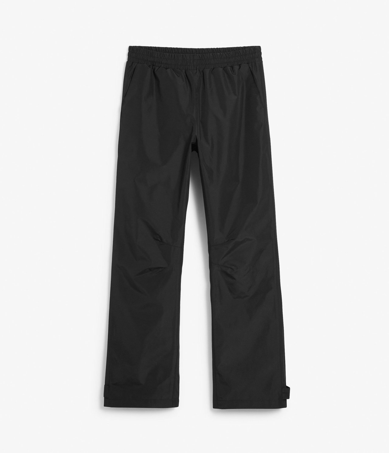 Edestä näkymä mustista vedenpitävistä kuorihousuista, joissa on joustava vyötärö.