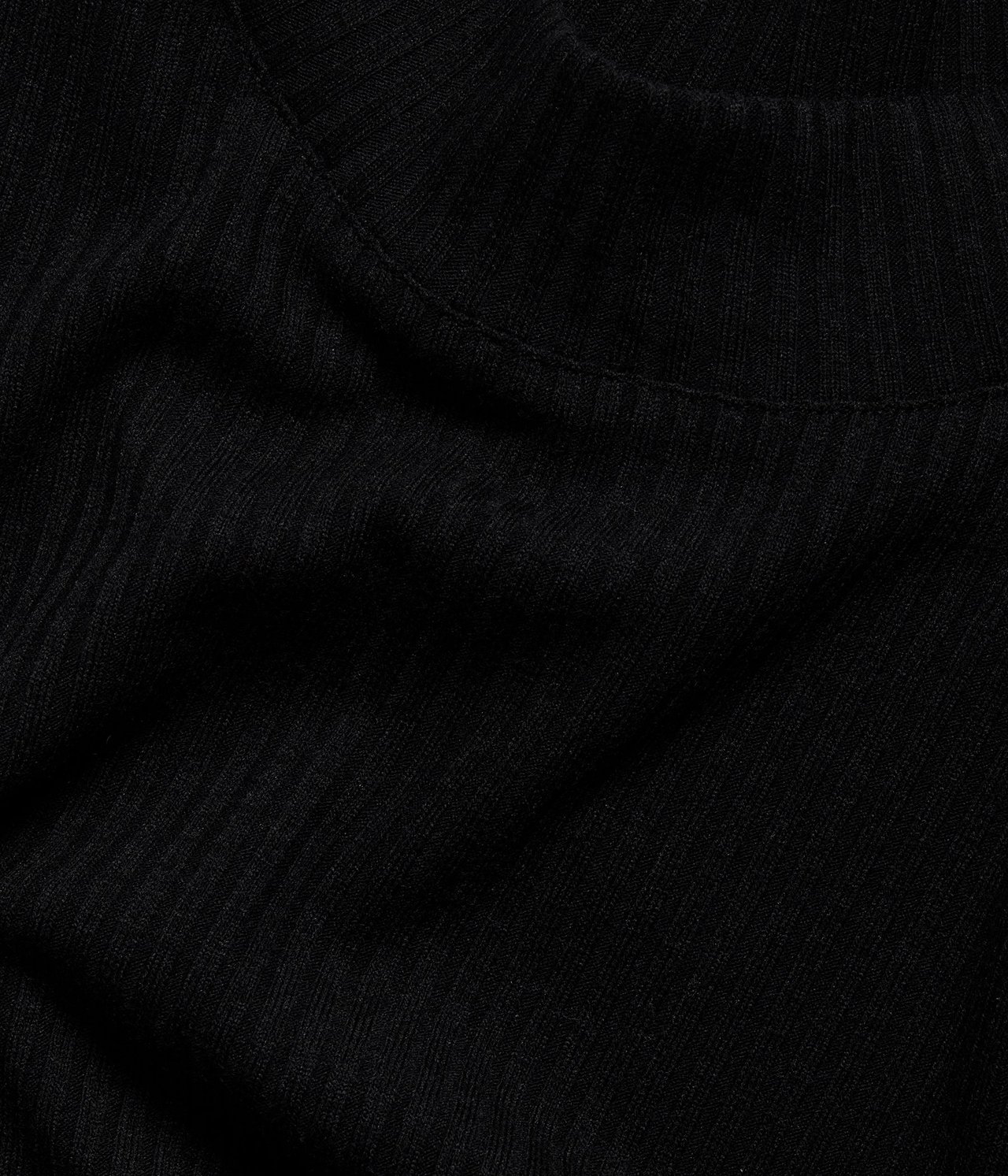 Zbliżenie czarnego, prążkowanego topu z golfem.