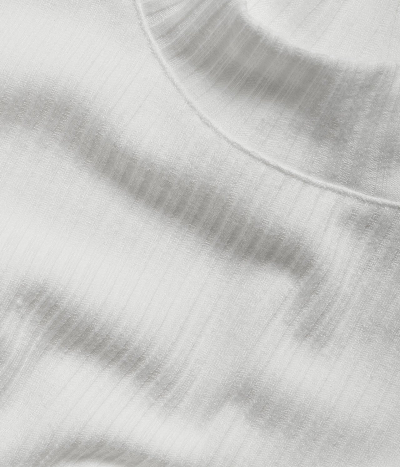 Zbliżenie na biały prążkowany top polo z krótkim rękawem, ukazujące fakturę materiału.