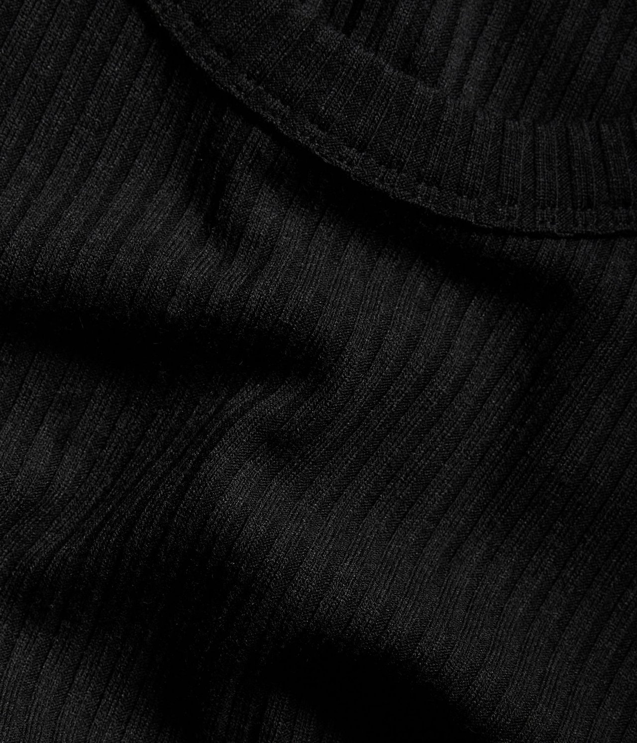 Zbliżenie czarnego prążkowanego topu, ukazujące teksturowany materiał.