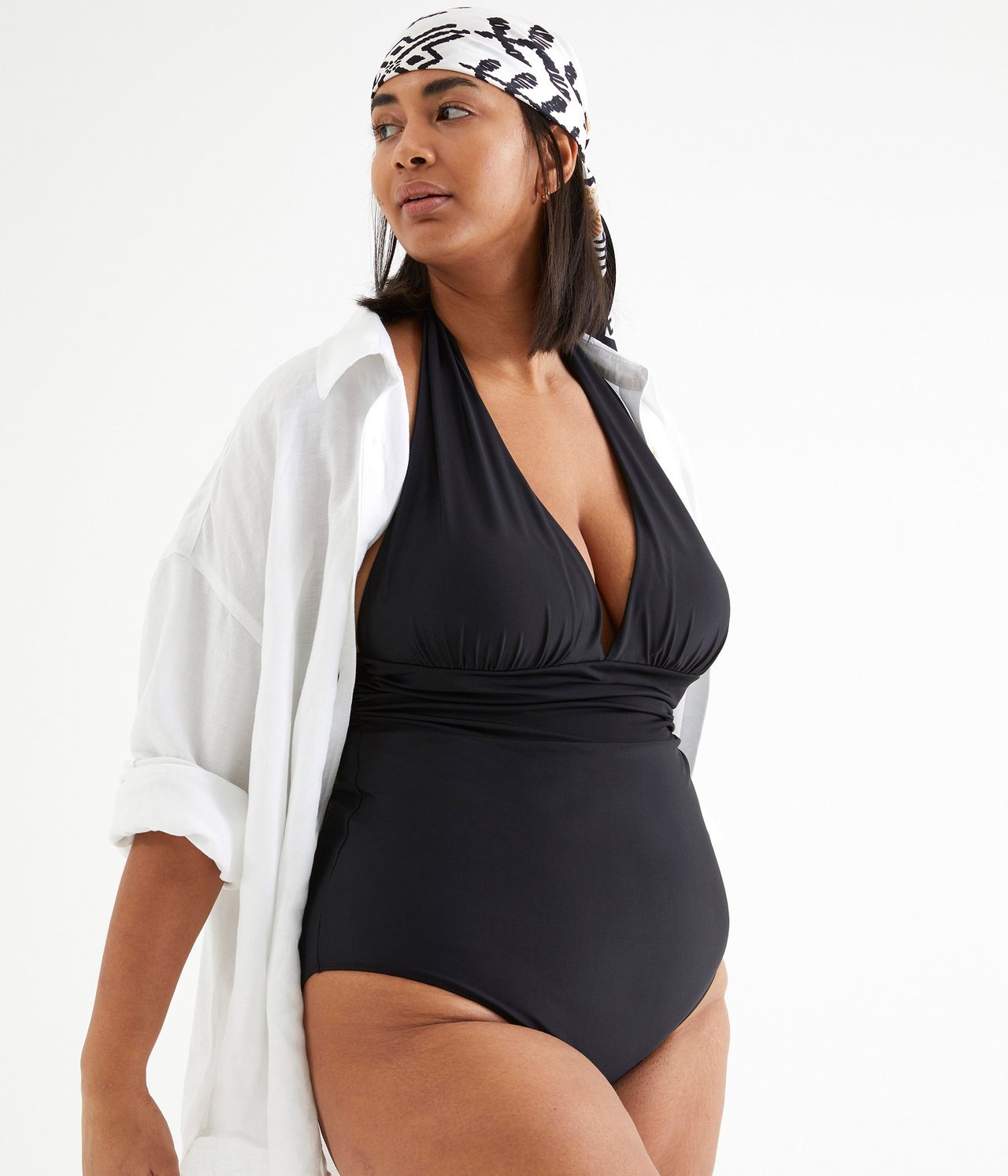 Widok z przodu kobiety w czarnym kostiumie kąpielowym wiązanym na szyi, białej koszuli i wzorzystej chuście.