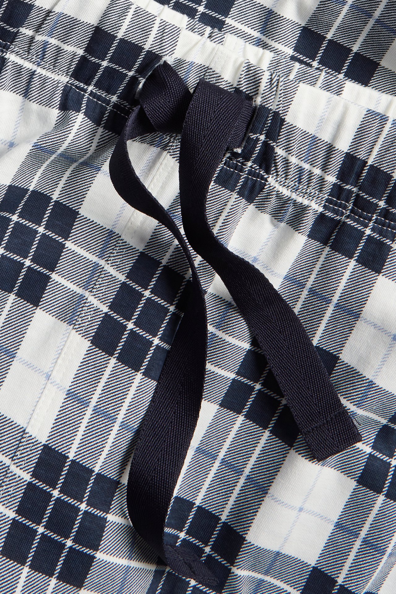 Närbild av mörkblå och vitrutiga pyjamasbyxor i bomull med resårlinning och mörkblå dragsko.