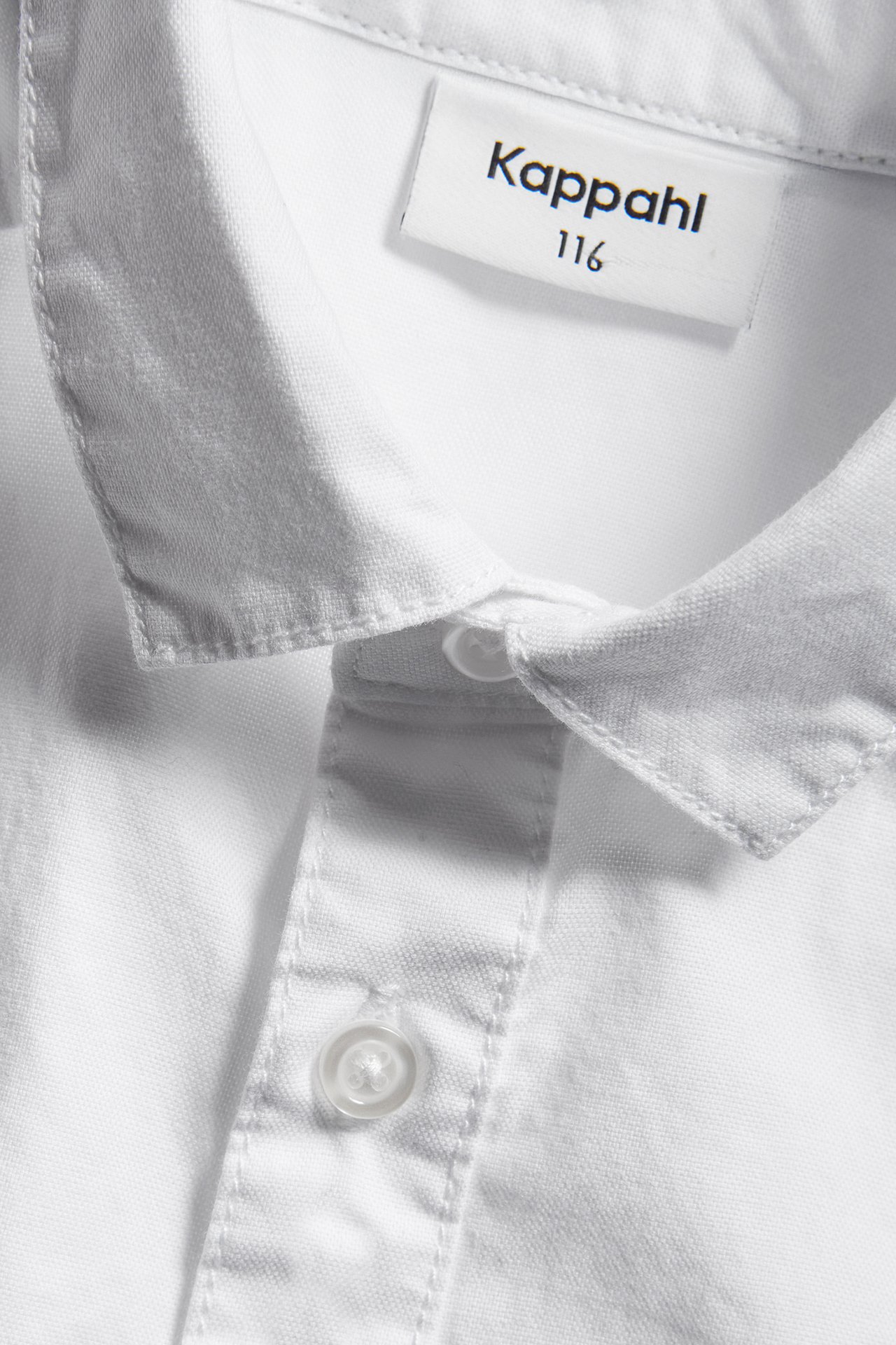 Zbliżenie na białą bawełnianą koszulę oxford dla dzieci, z kołnierzem i listwą z guzikami.