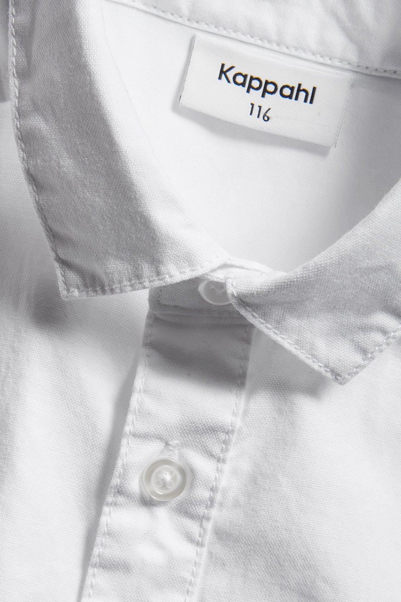 Zbliżenie na białą bawełnianą koszulę oxford dla dzieci, z kołnierzem i listwą z guzikami.