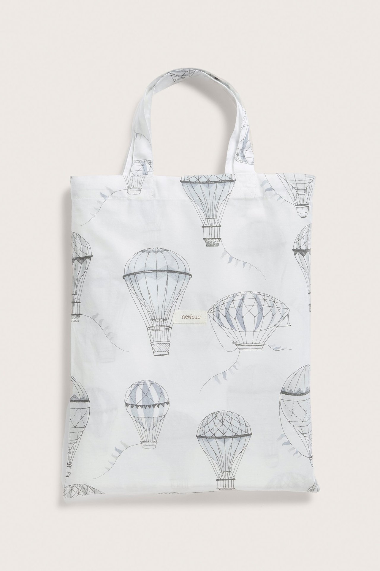 Framsida av en offwhite bomullstygkasse med grått luftballongsmönster och två handtag.