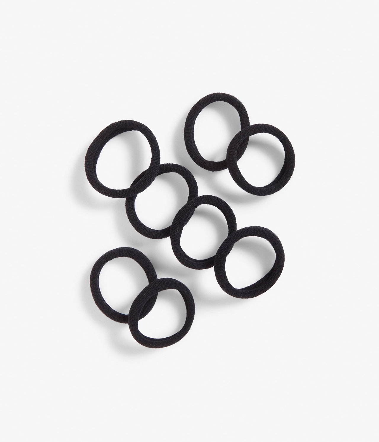 Ylhäältä kuvattu kahdeksan mustaa joustavaa hiuslenkkiä valkoisella pinnalla.