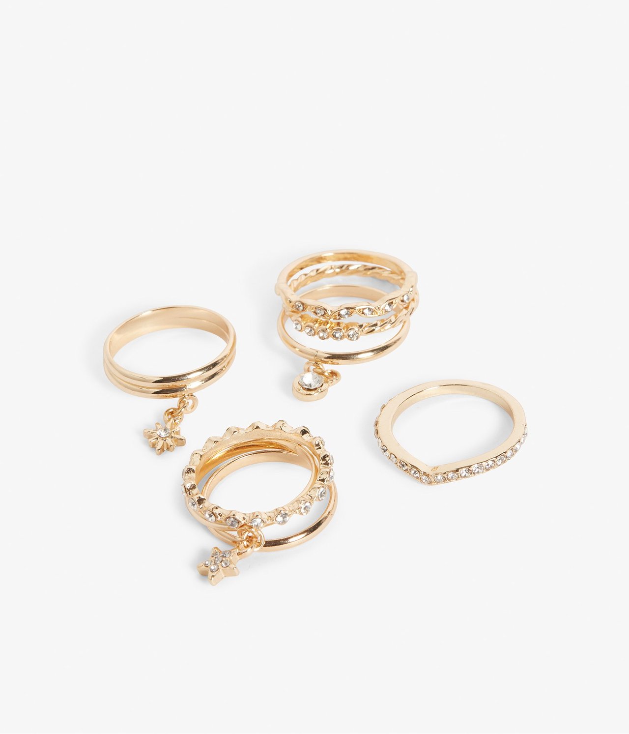 Zbliżenie na zestaw złotych pierścionków, niektóre z cyrkoniami i zawieszkami gwiazd lub kółek.