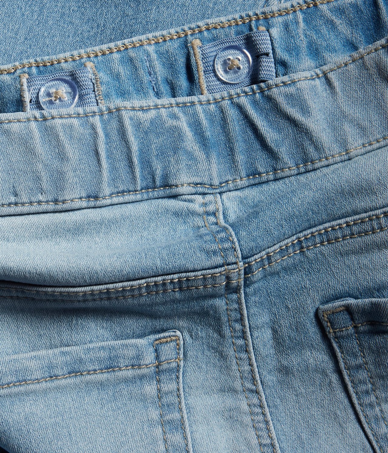 Zbliżenie tyłu dziecięcych jasnych dżinsowych jegginsów bootcut z regulowaną gumką w pasie i tylnymi kieszeniami.