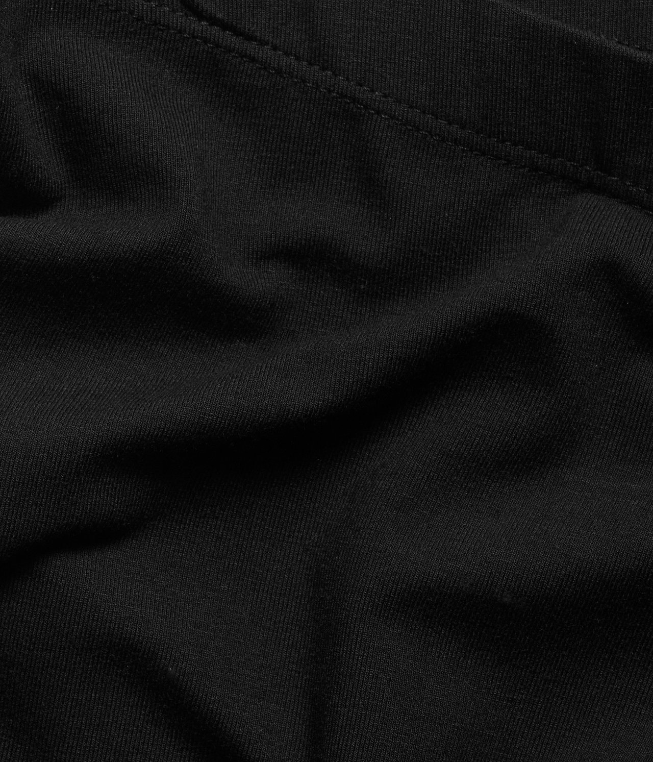 Zbliżenie czarnego materiału dżersejowych spodenek rowerowych z widocznymi szwami.