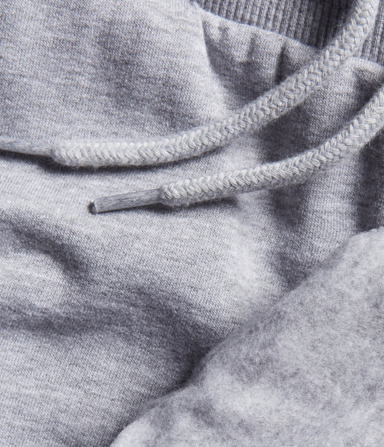 Zbliżenie szarych melanżowych spodni dresowych, ukazujące miękki materiał i sznurek ściągający.