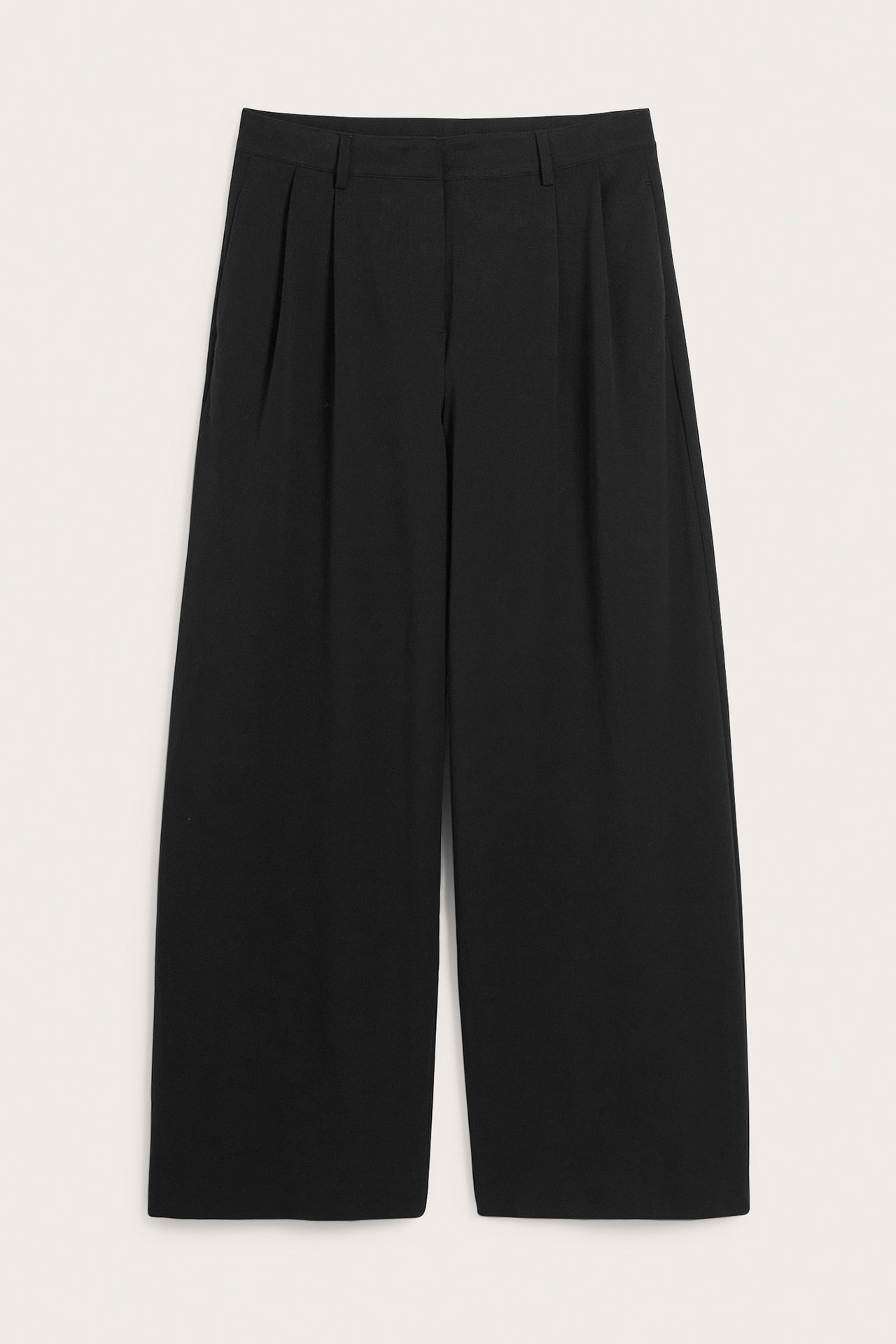 Edestä, mustat leveälahkeiset suorat housut laskoksilla vyötäröllä.