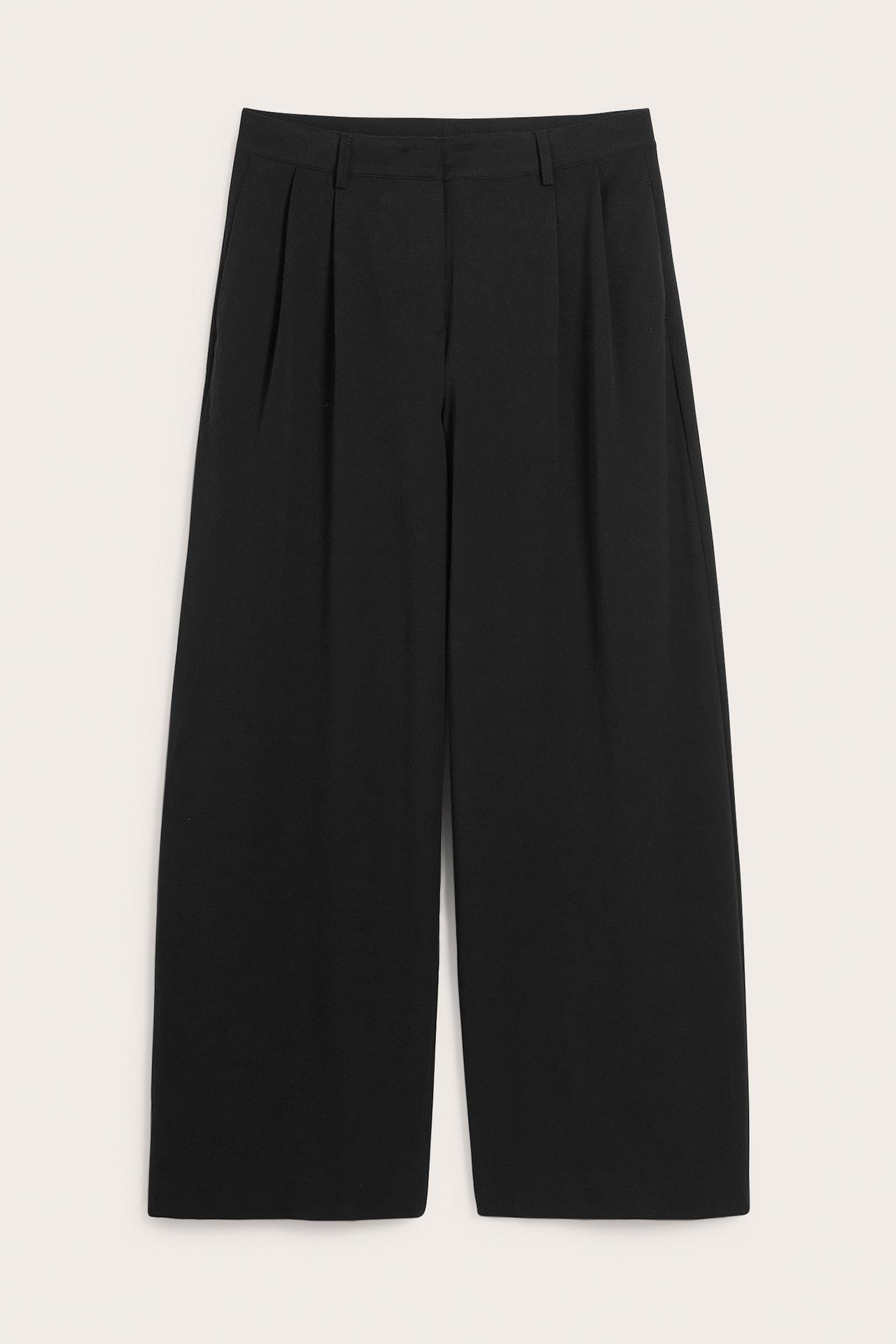 Edestä, mustat leveälahkeiset suorat housut laskoksilla vyötäröllä.