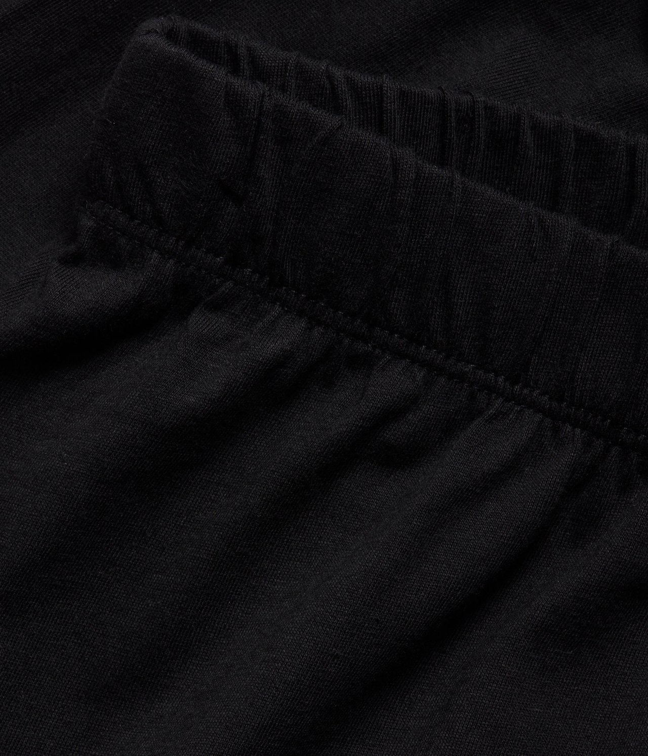 Zbliżenie czarnych szortów piżamowych z bawełnianej dzianiny z ukrytą gumką w pasie.