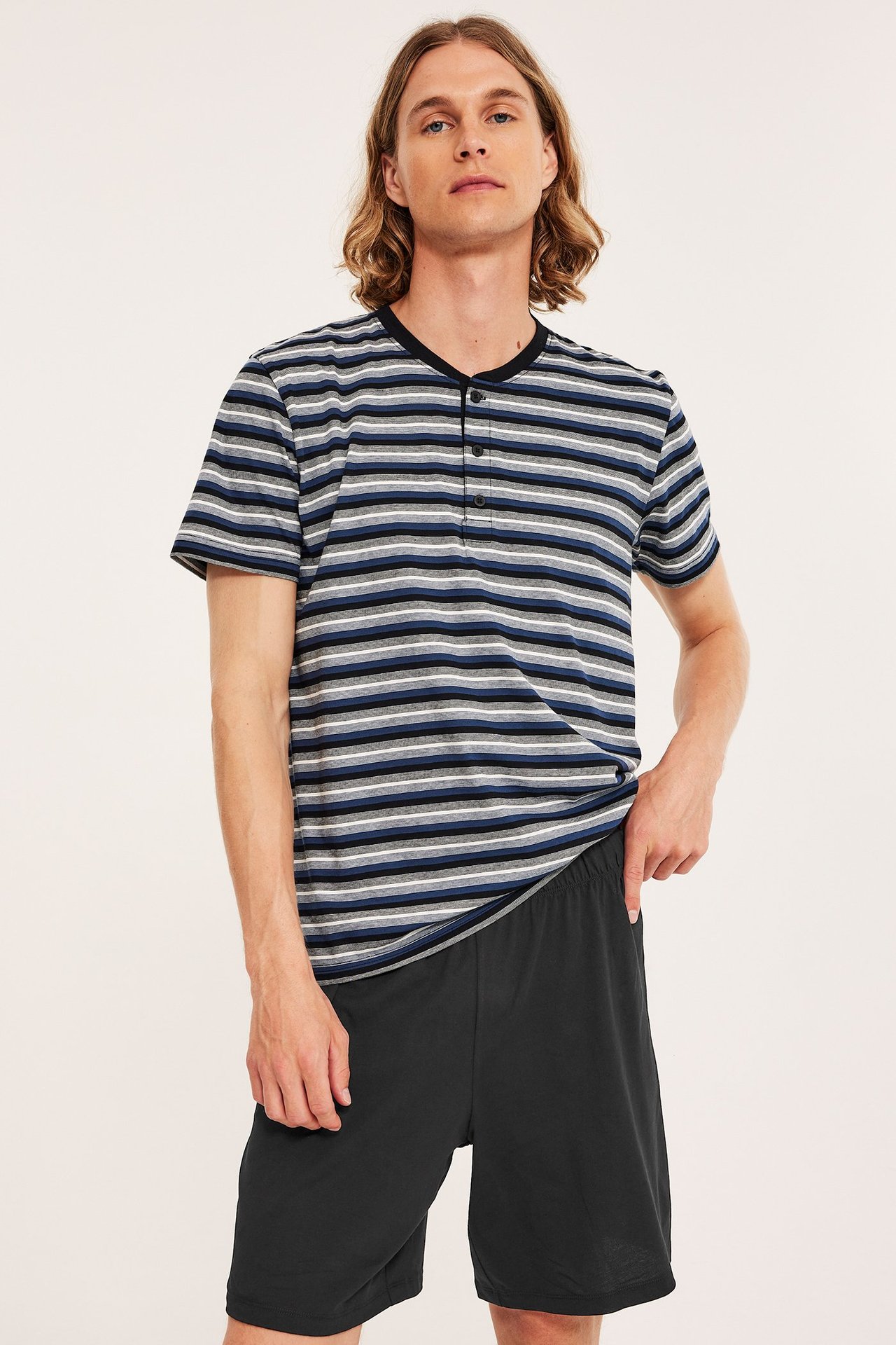 Edestäpäin mies mustissa jersey-pyjamashortseissa ja raidallisessa lyhythihaisessa Henley-paidassa.