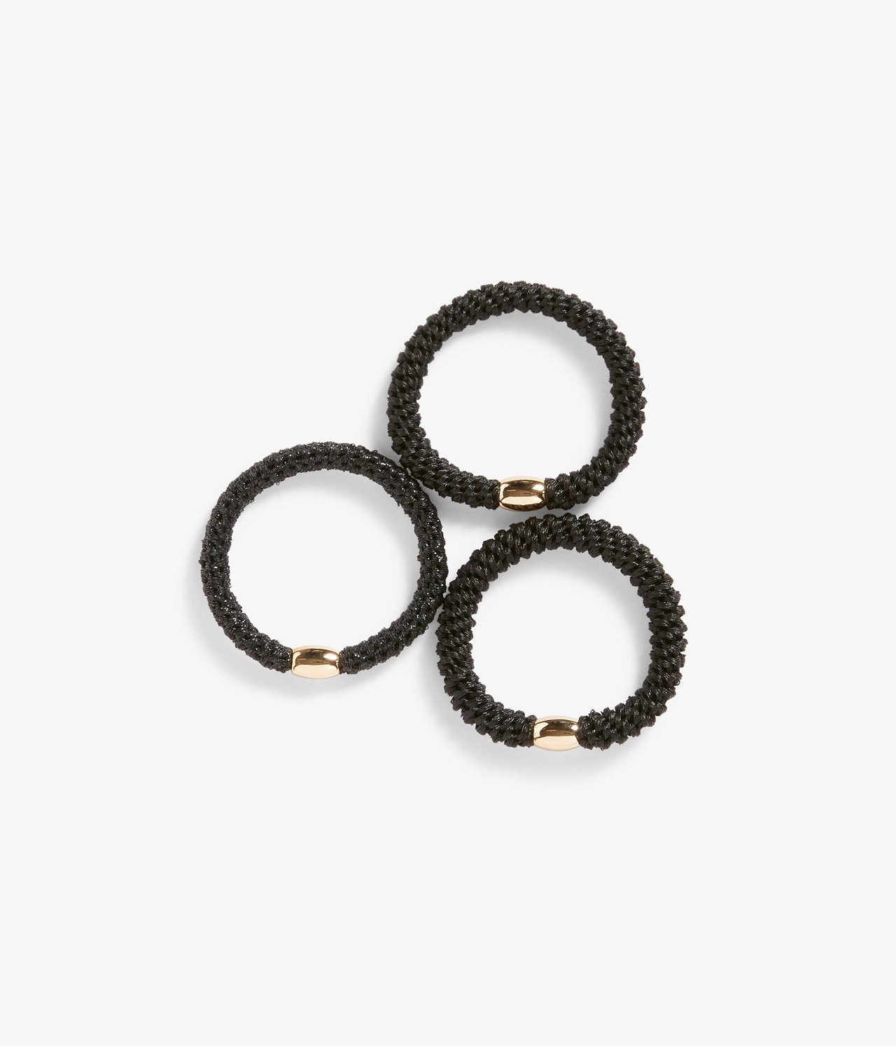 Ylhäältä kuvattuna kolme mustaa punottua hiuslenkkiä, joissa jokaisessa on kullanvärinen helmi.