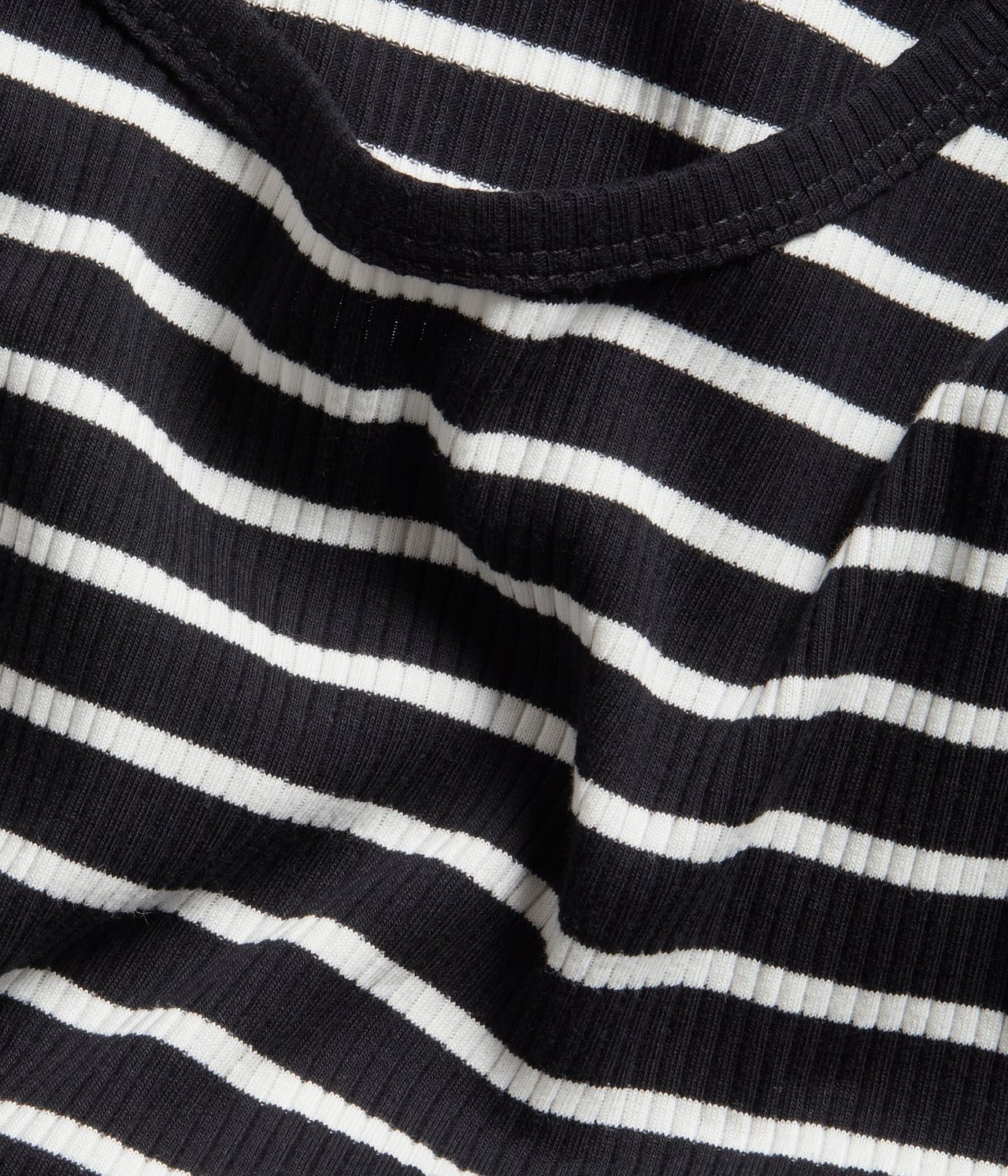 Zbliżenie czarno-białej, prążkowanej bluzki z długim rękawem w paski.