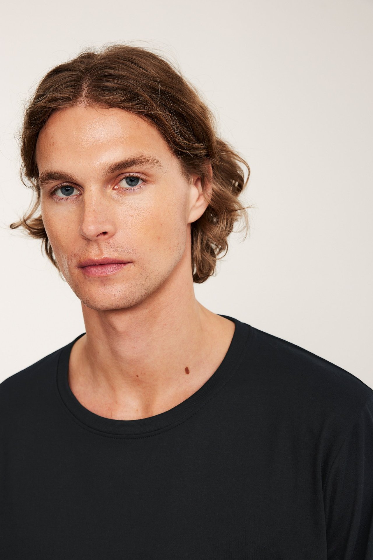 Lähikuva miehestä yllään musta, yksivärinen puuvillainen pyjamapaita.