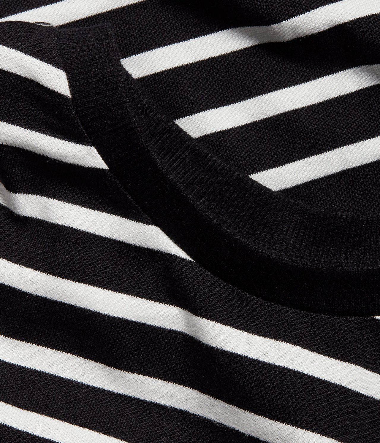 Zbliżenie czarno-białej bluzki w paski z bawełnianego dżerseju z prążkowanym dekoltem.
