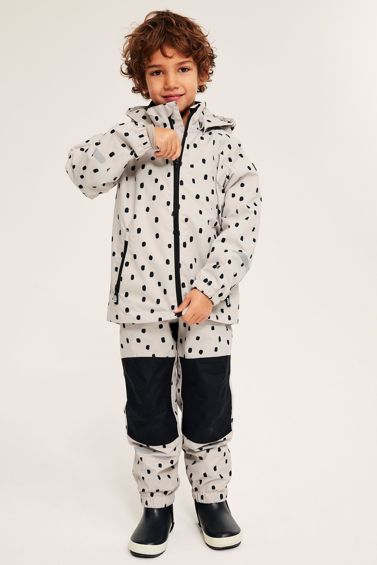 Barn i beige, mønstret vanntett skaljakke med hette, glidelås, justerbar ermelengde og reflekser.