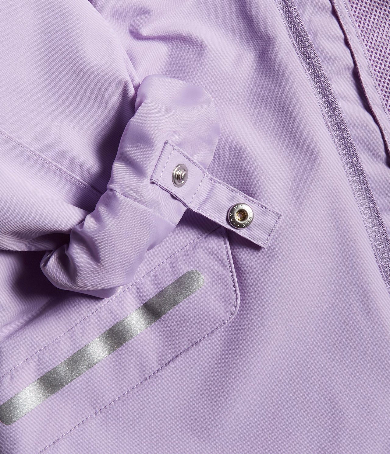 Zbliżenie liliowej wodoodpornej kurtki softshell z zatrzaskiem, paskiem odblaskowym i zamkiem.