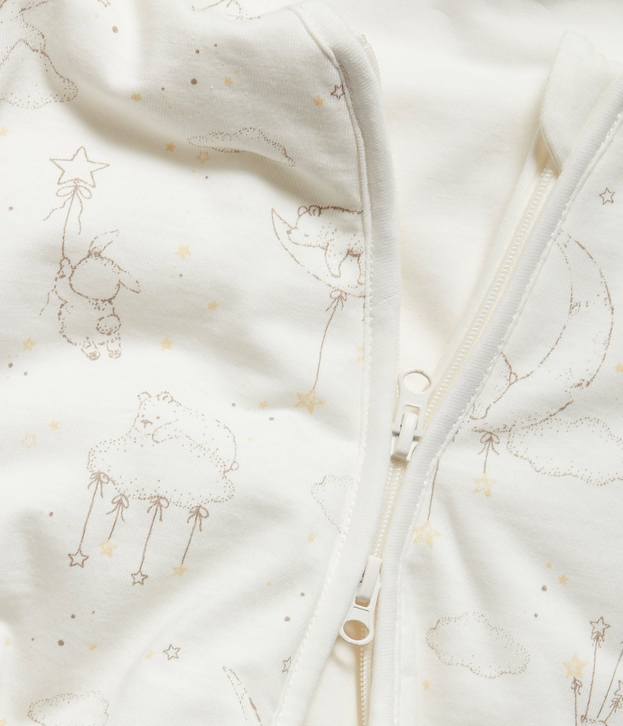 Närbild: Offwhite babysovpåse med mönster av björnar, kaniner, moln och tvåvägsdragkedja.