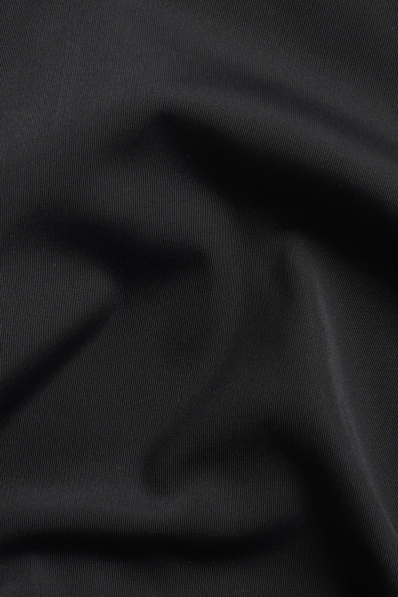 Zbliżenie na czarny, jednolity materiał mikrofibrowy na figi typu hipster.