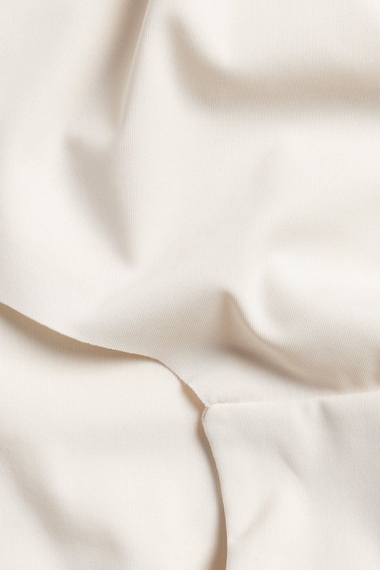 Zbliżenie beżowego, jednolitego, miękkiego materiału z mikrofibry na figi typu hipster.