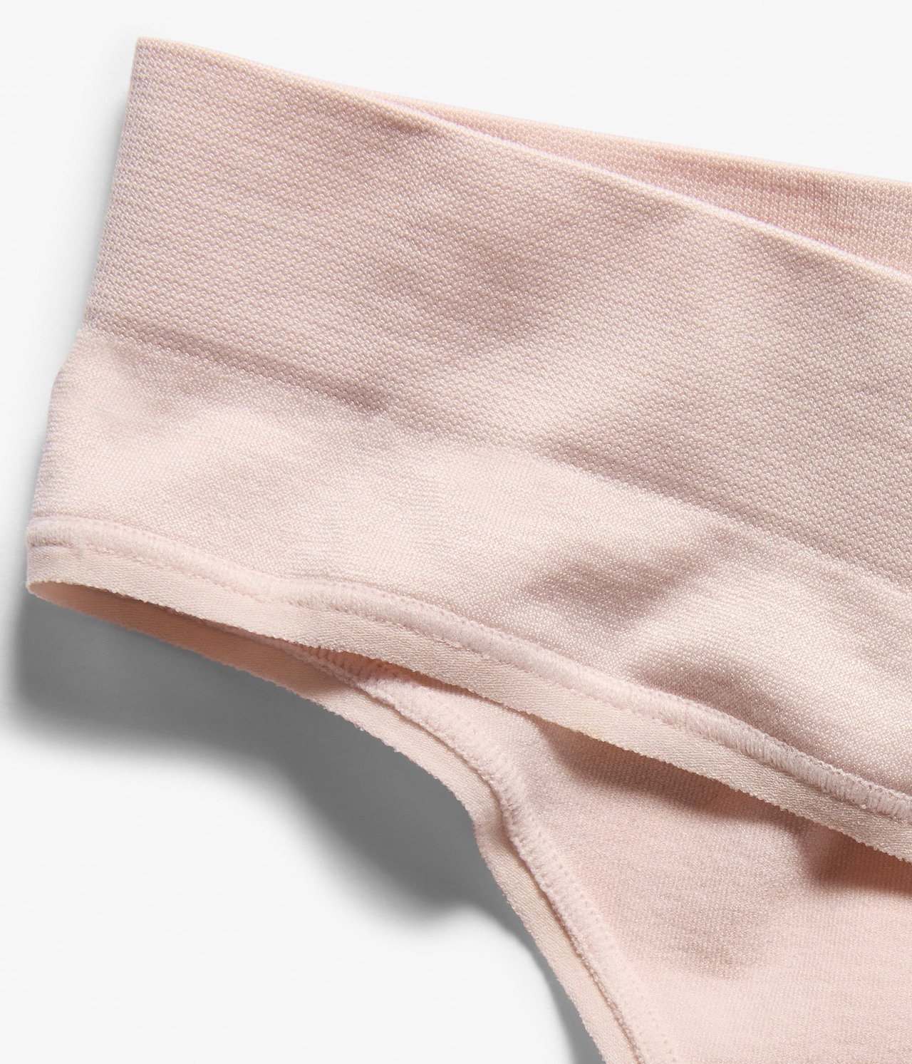 Zbliżenie jasnoróżowych, bezszwowych stringów z szerokim pasem.