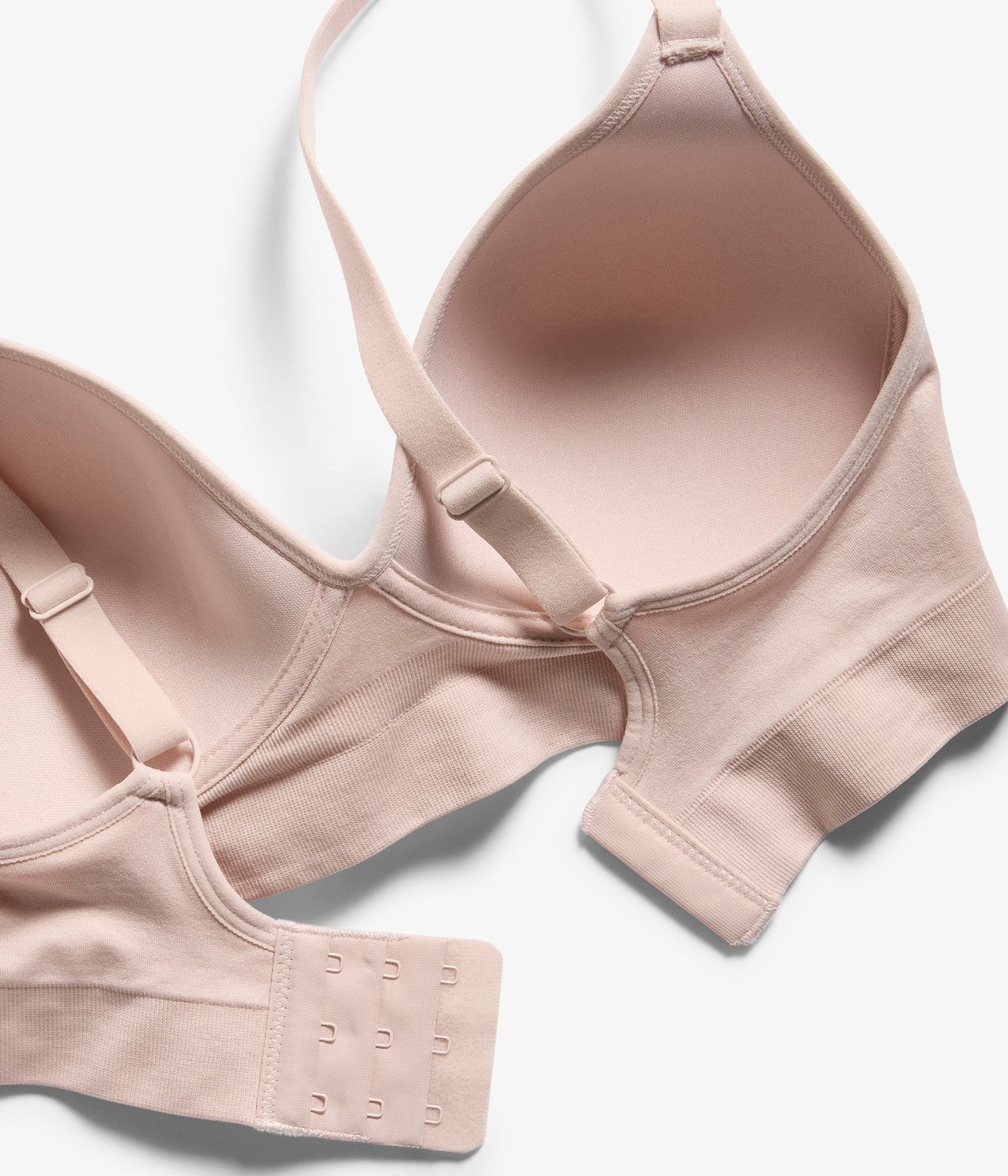 Zbliżenie jasnoróżowego, bezszwowego biustonosza soft z formowanymi miseczkami i zapięciem na haftki.