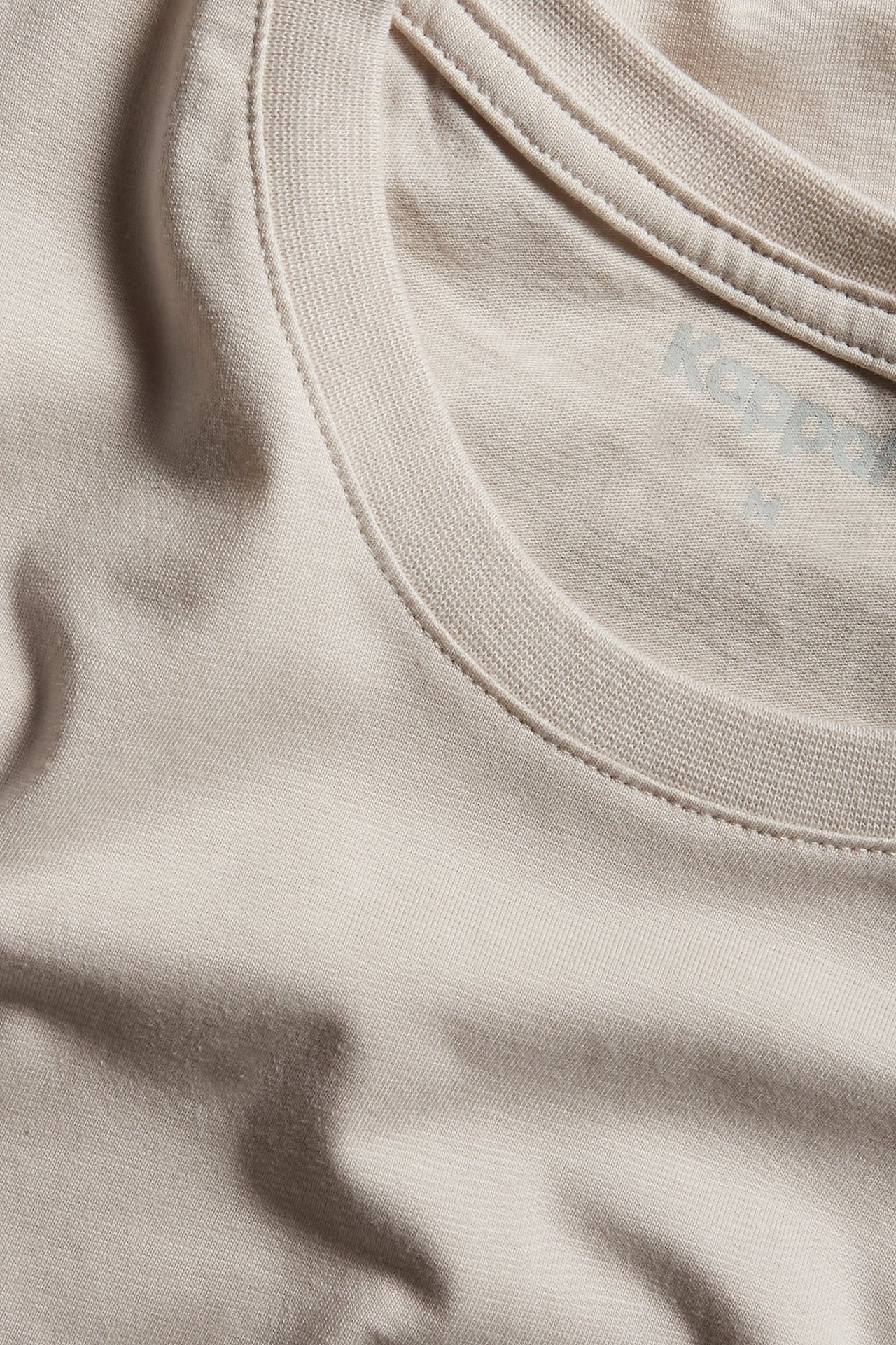 Zbliżenie na męski, gładki, jasnobeżowy bawełniany t-shirt z okrągłym dekoltem.