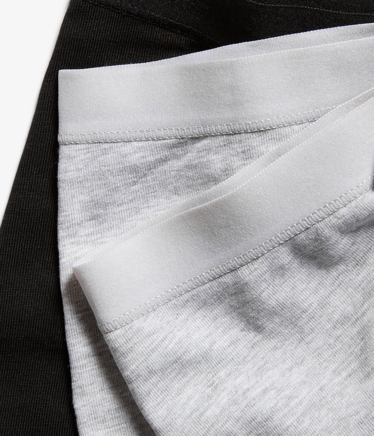 Zbliżenie na złożone szare melanżowe bawełniane bokserki z elastycznym pasem, obok czarnej pary.