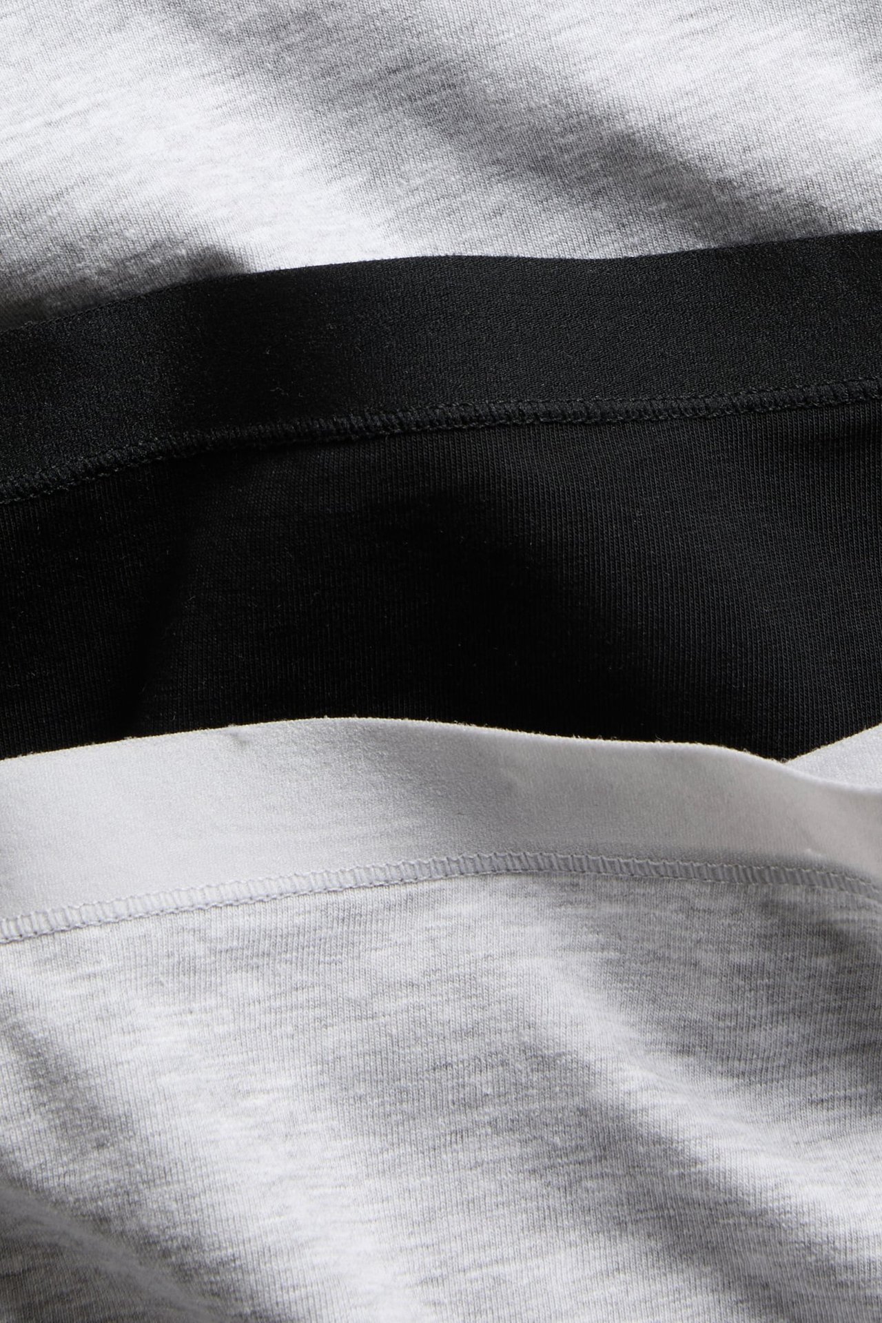 Lähikuva pinotuista naisten puuvillabokserishortseista: harmaameleerattu, musta ja harmaa valkoisella vyötärönauhalla.