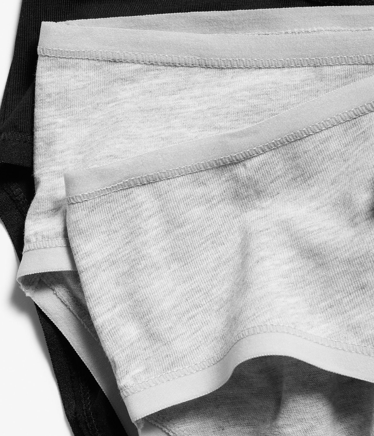 Zbliżenie złożonych szarych melanżowych i czarnych bawełnianych majtek z elastycznymi brzegami.