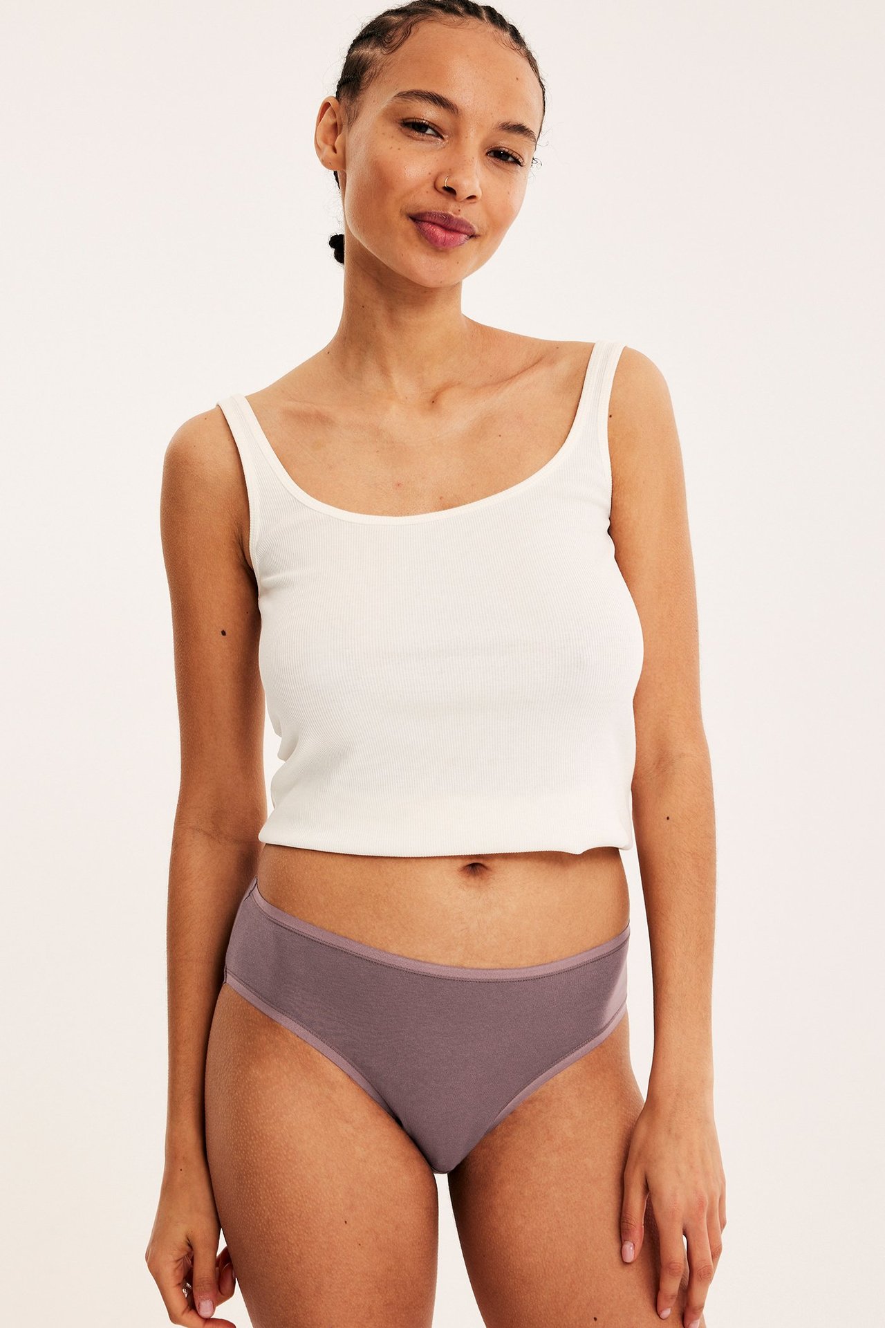 Forfra, kvinne i mauvefargede bomullstruser og hvit ribbet singlet.