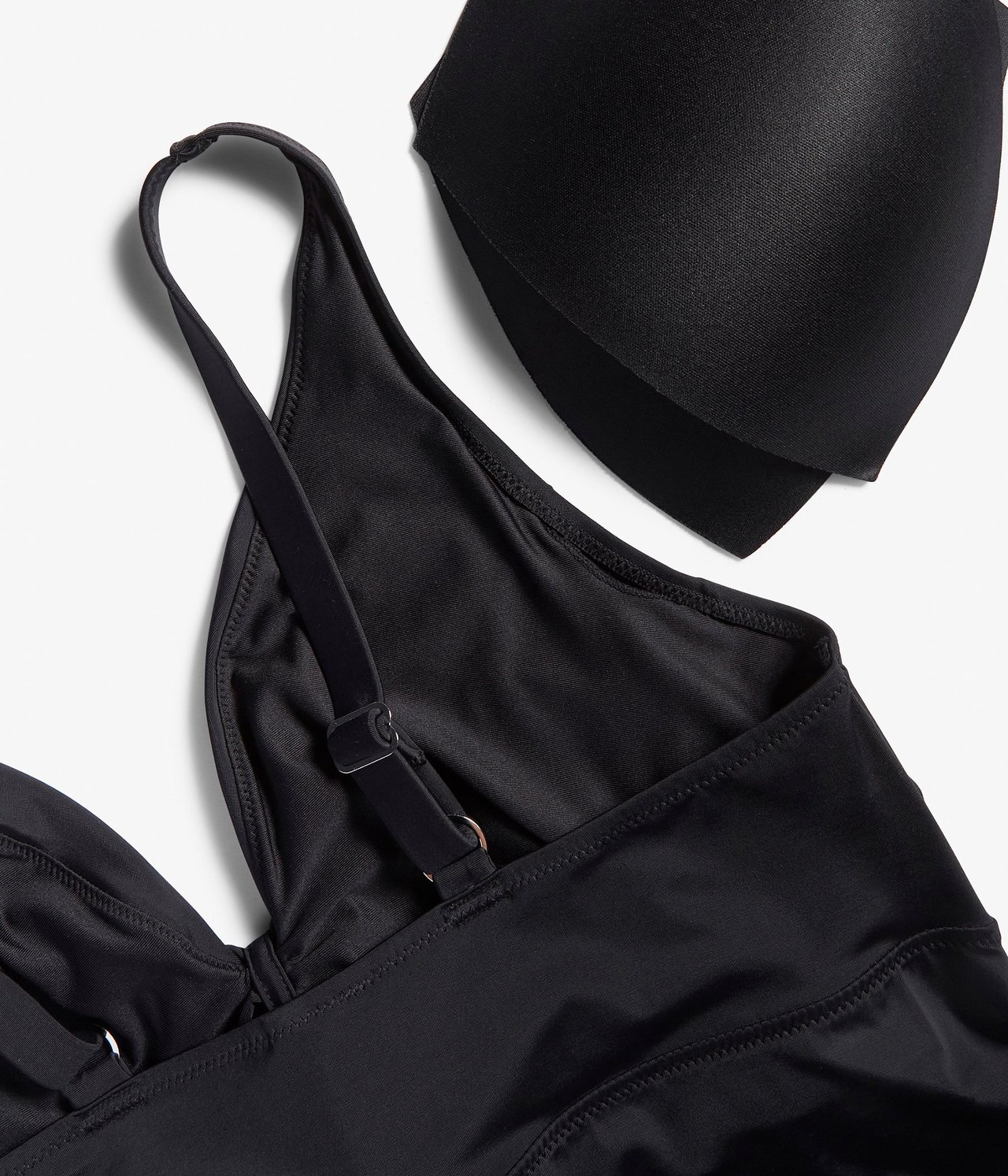 Zbliżenie czarnego biustonosza bikini z regulowanymi ramiączkami, marszczeniem i wycięciem, z czarną wkładką biustonosza.