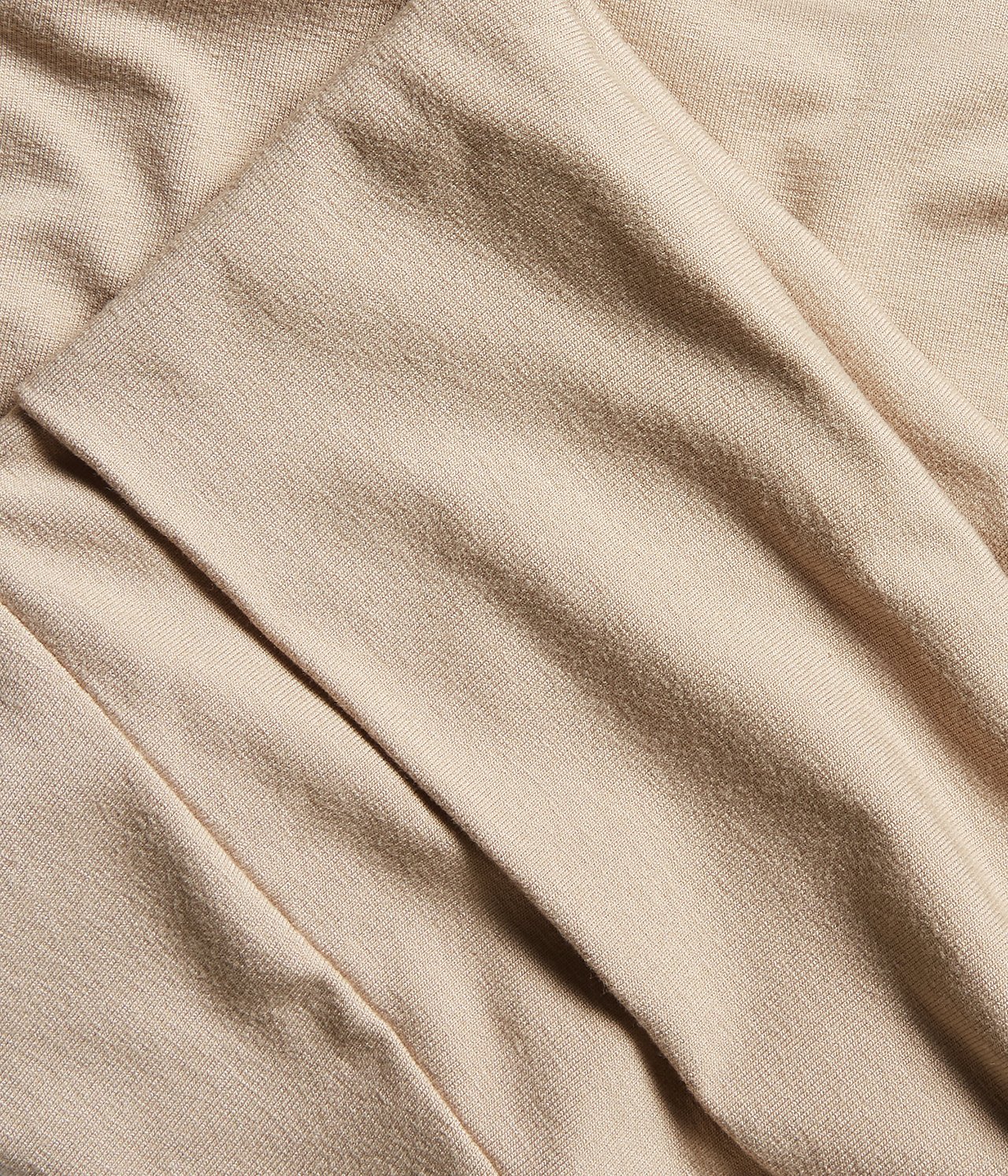 Zbliżenie na beżowy materiał wiskozowy legginsów loungewear z delikatnymi fałdami.