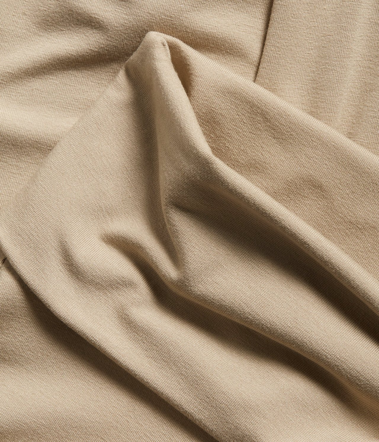 Zbliżenie na miękki, jednolity beżowy materiał wiskozowy na spodnie loungewear.