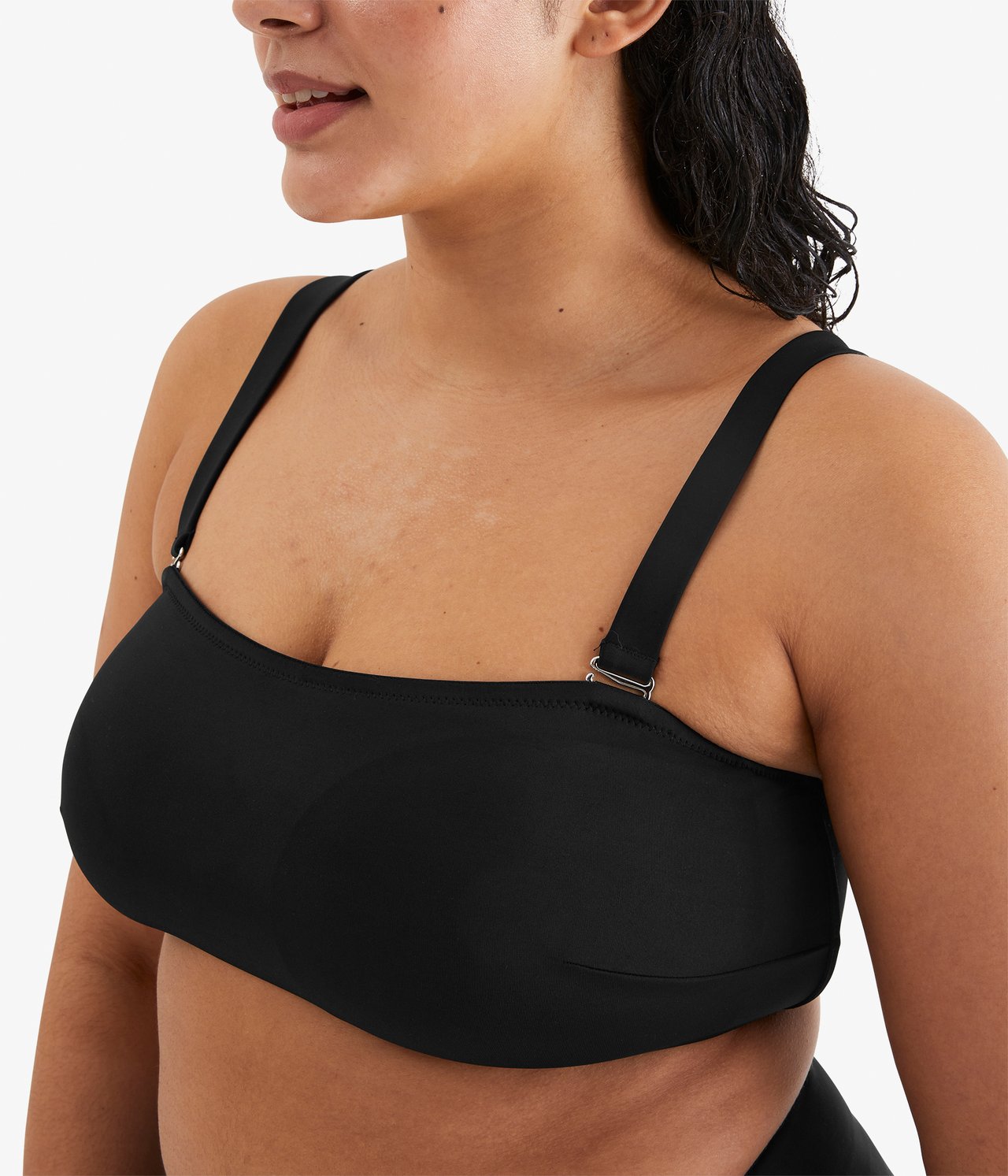 Nærbilde, forfra av en kvinne i svart strukturert bandeau-bikinitopp med tynne stropper.