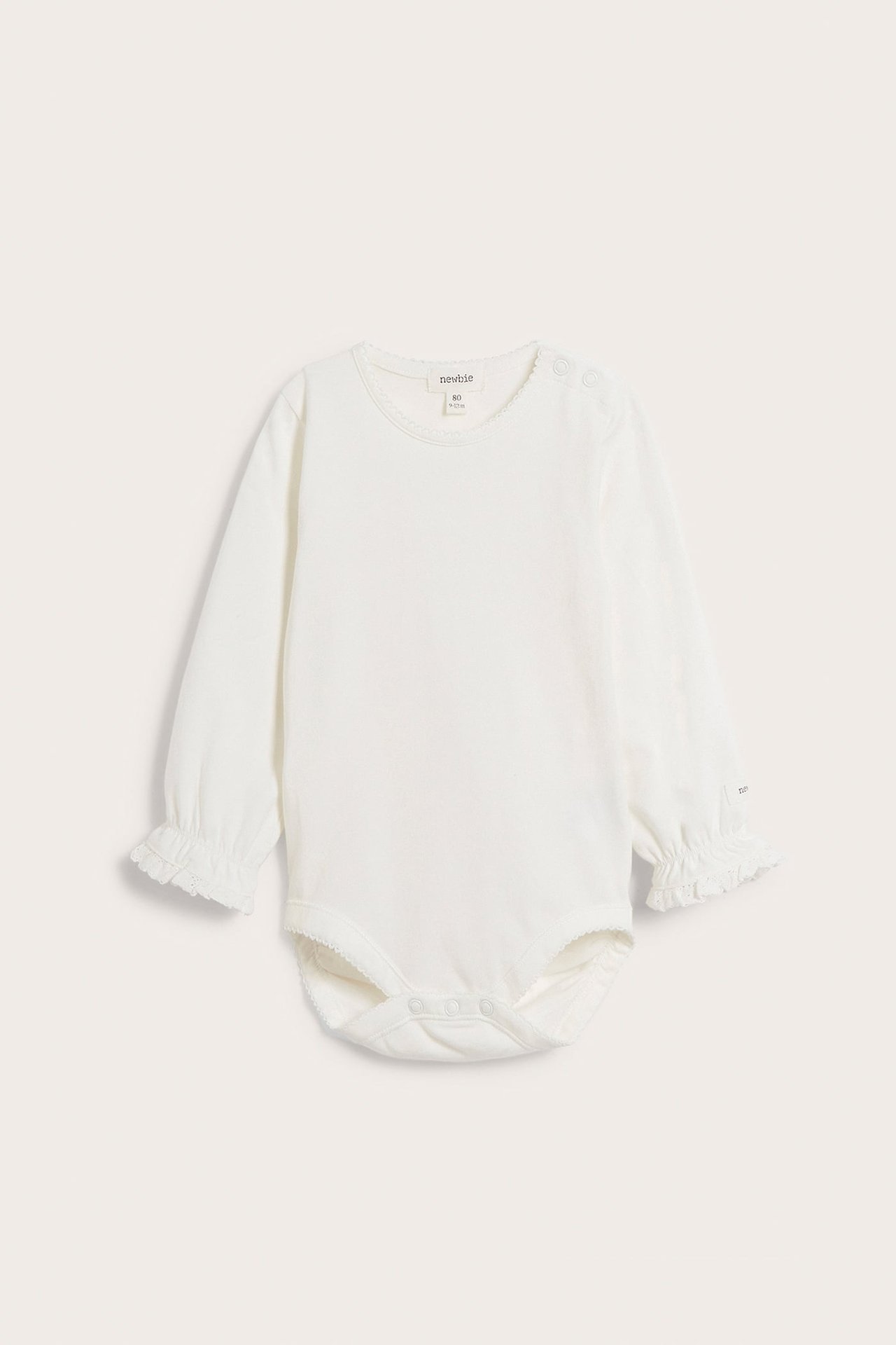 Frontvy av en offwhite långärmad babybody med picotkant i halsringning, spetsvolangärmslut och tryckknappar.