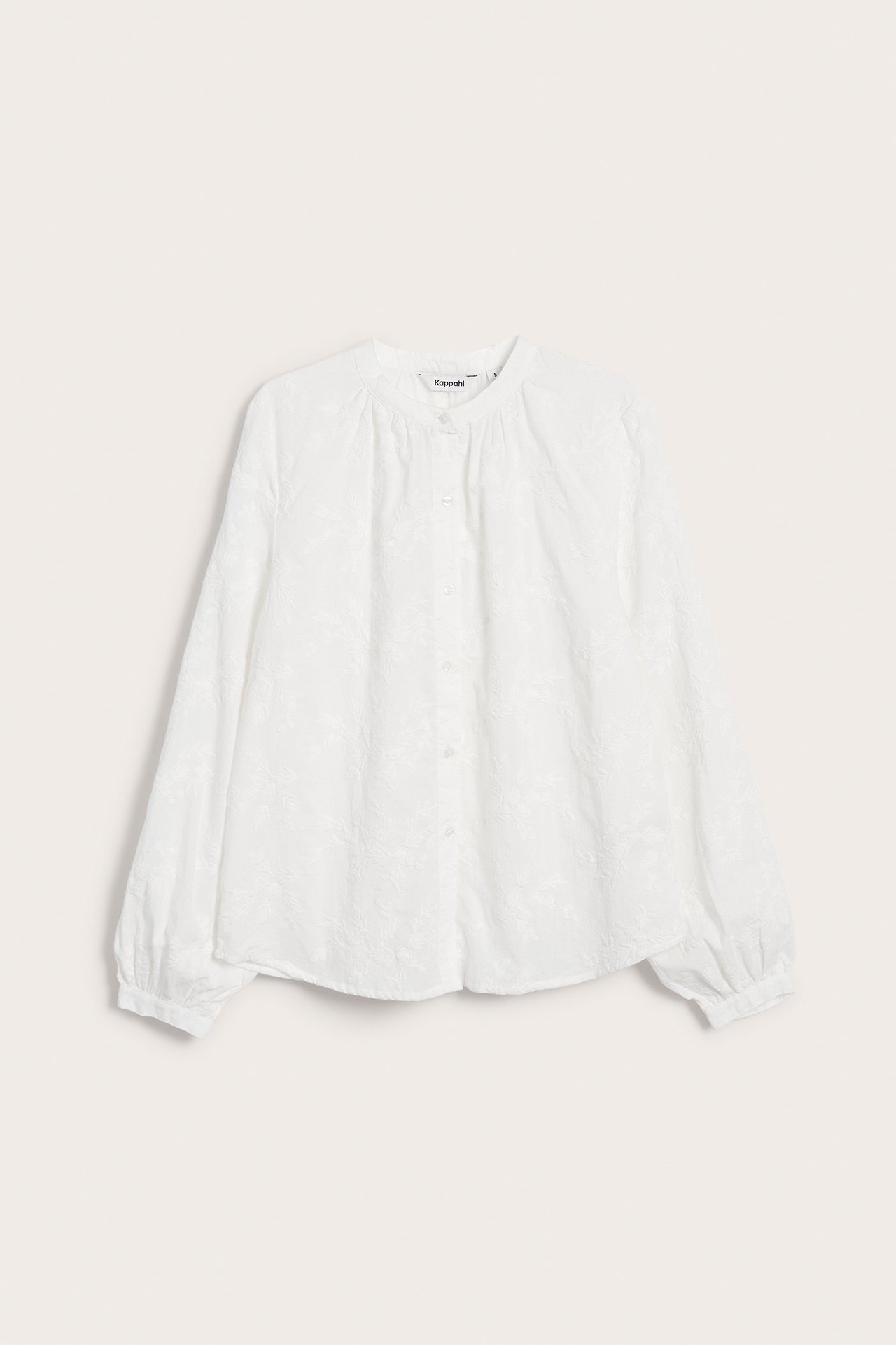 Widok z przodu kremowej bawełnianej bluzki ze stójką, guzikami i subtelnym haftowanym wzorem kwiatowym.