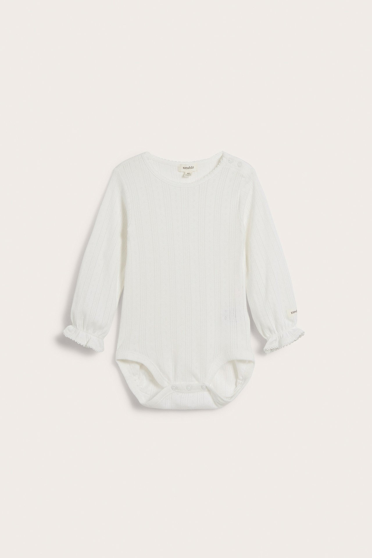 Forfra av en hvit ribbestrikket langermet babybody med rysjede mansjetter og trykknapper.